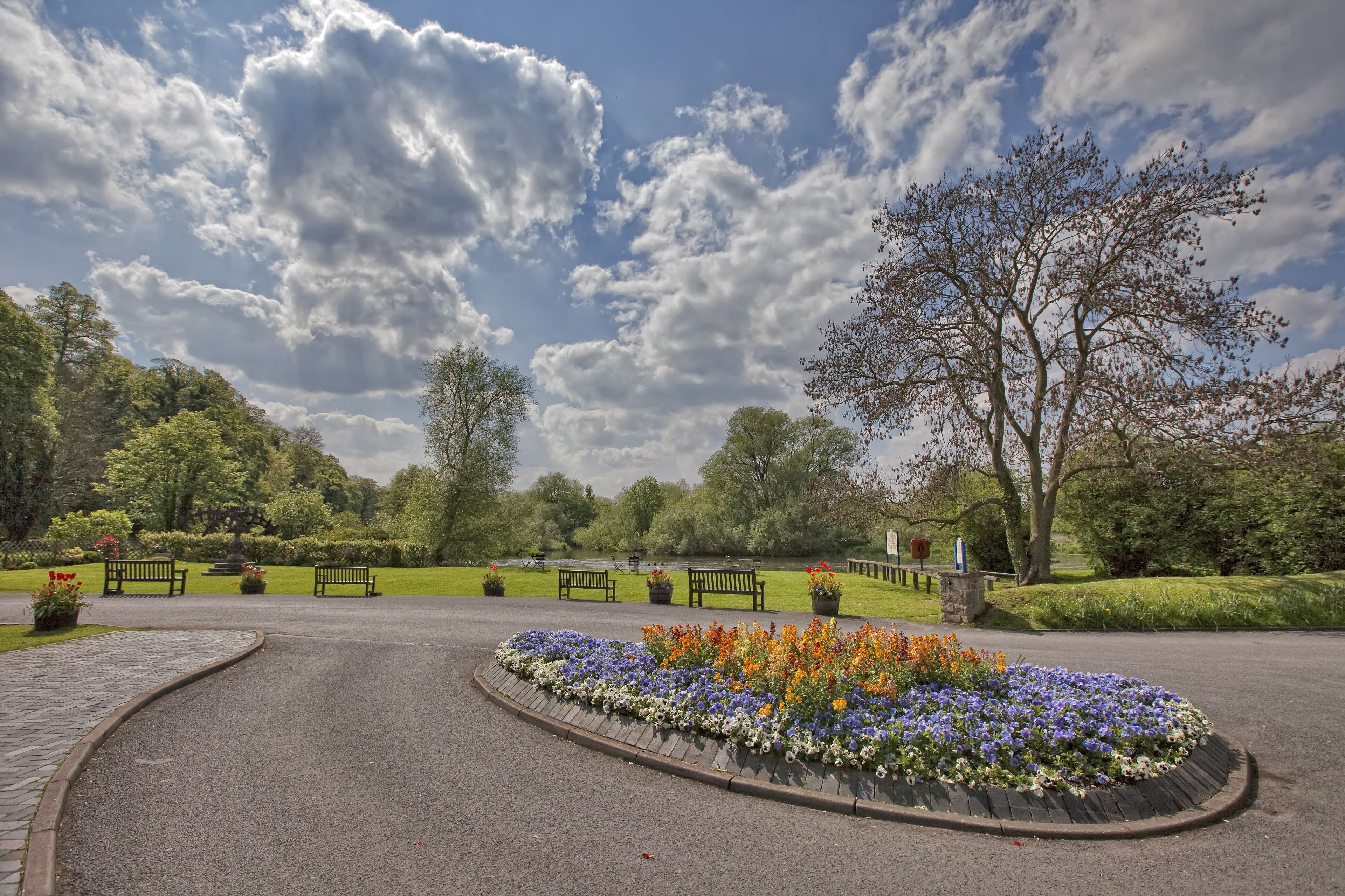A park with a paved path, benches, and flower beds.