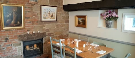 A dining area with a brick fireplace, wooden table, and chairs.