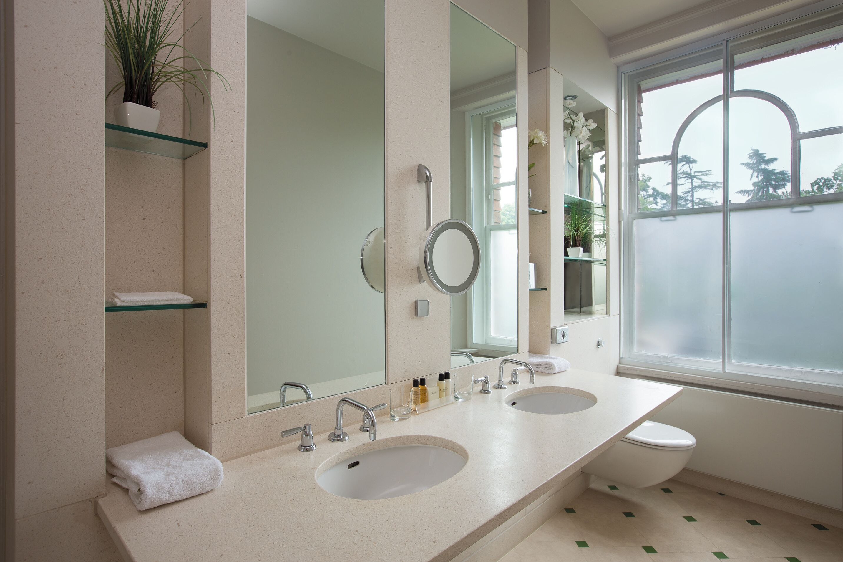 A modern bathroom with two sinks, a large mirror, and a window with a view.