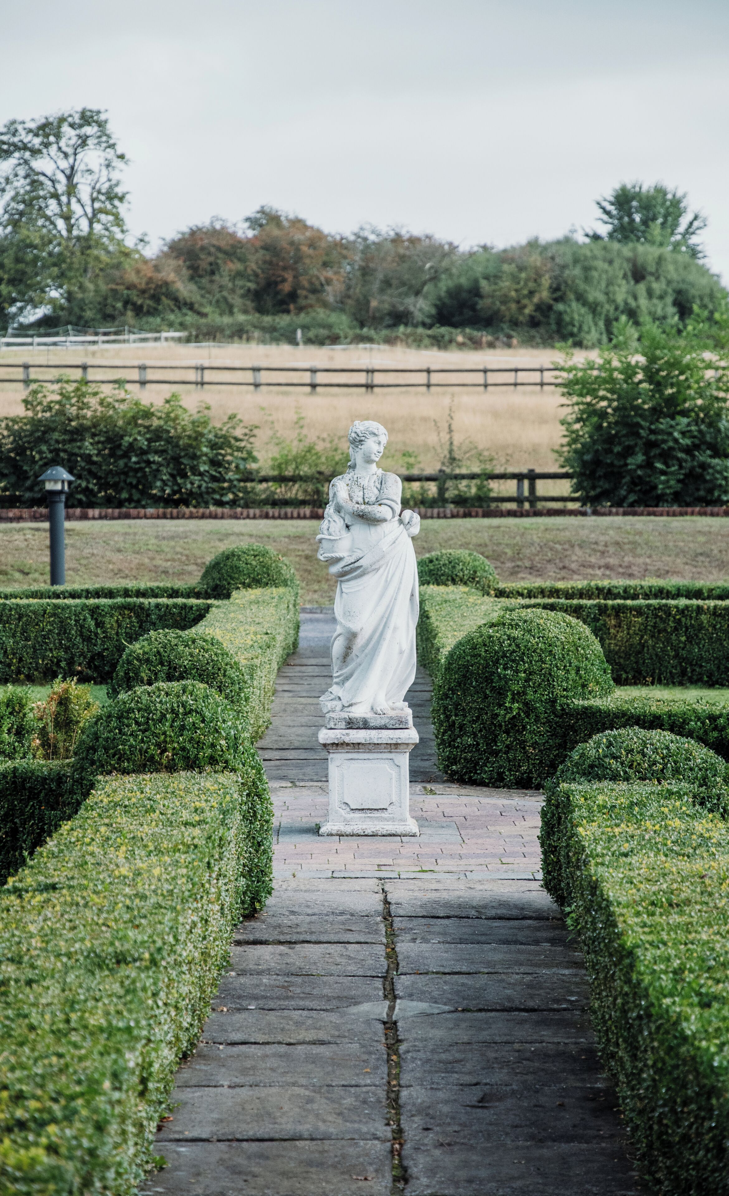 A statue in a garden with a paved path.