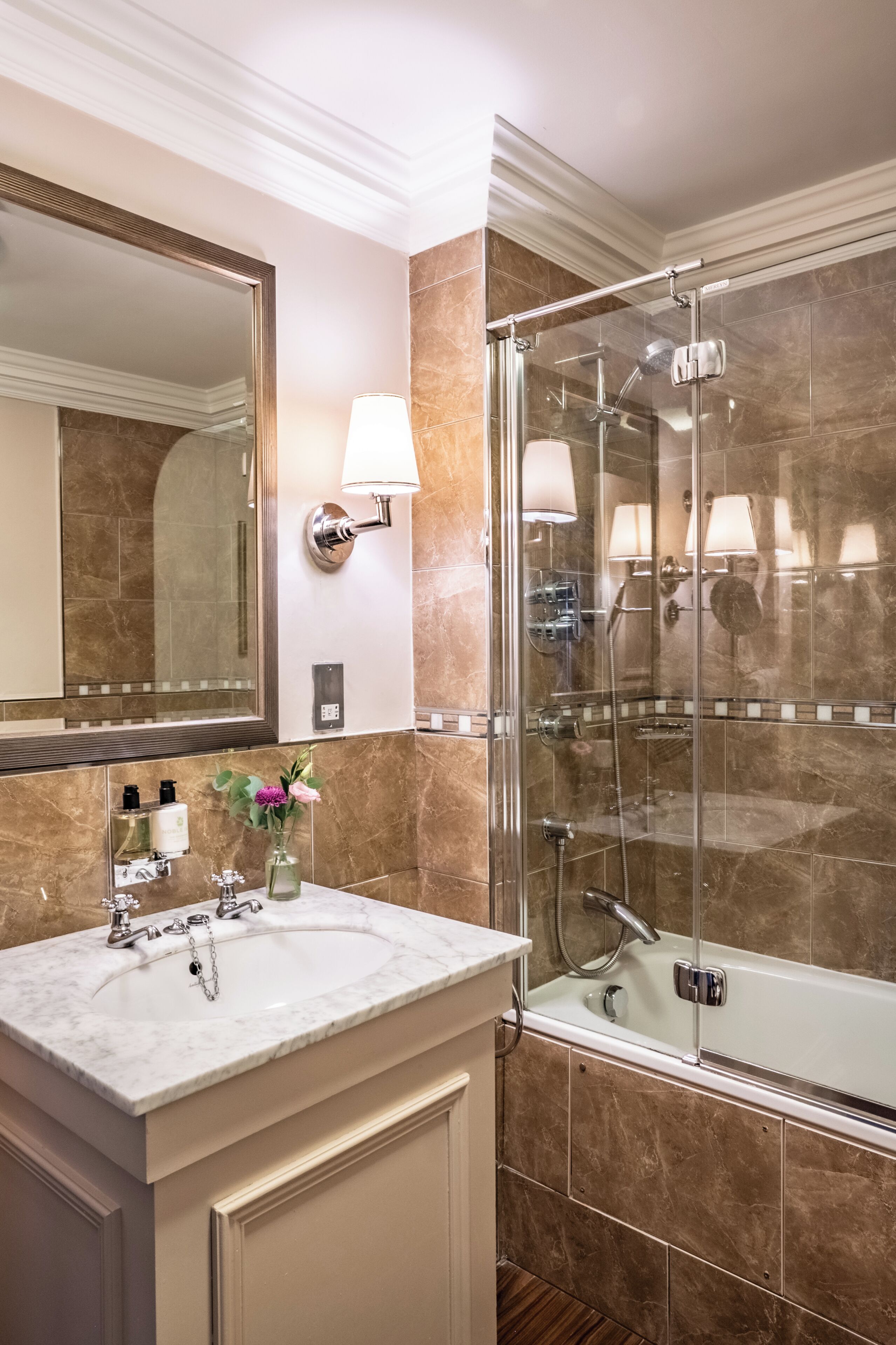 Un baño con lavamanos de mármol, un espejo grande, cabina de ducha con vidrio y bañera.