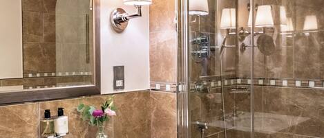 Un baño con lavamanos de mármol, un espejo grande, cabina de ducha con vidrio y bañera.