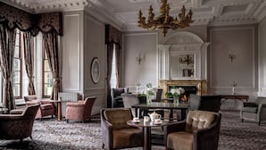 A formal room with a fireplace, elegant chairs, and a patterned carpet. - Crathorne Hall Hotel (Yarm)