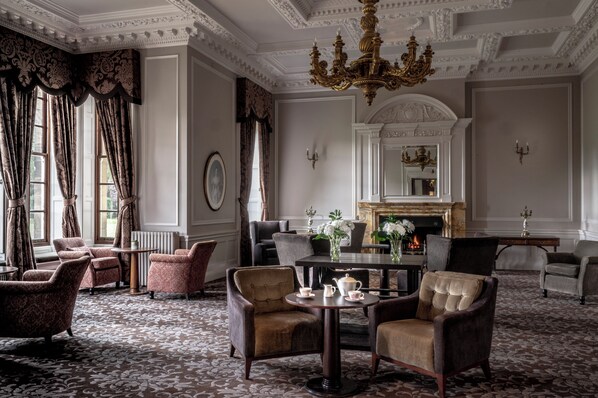 A formal room with a fireplace, elegant chairs, and a patterned carpet. - Crathorne Hall Hotel (Yarm)