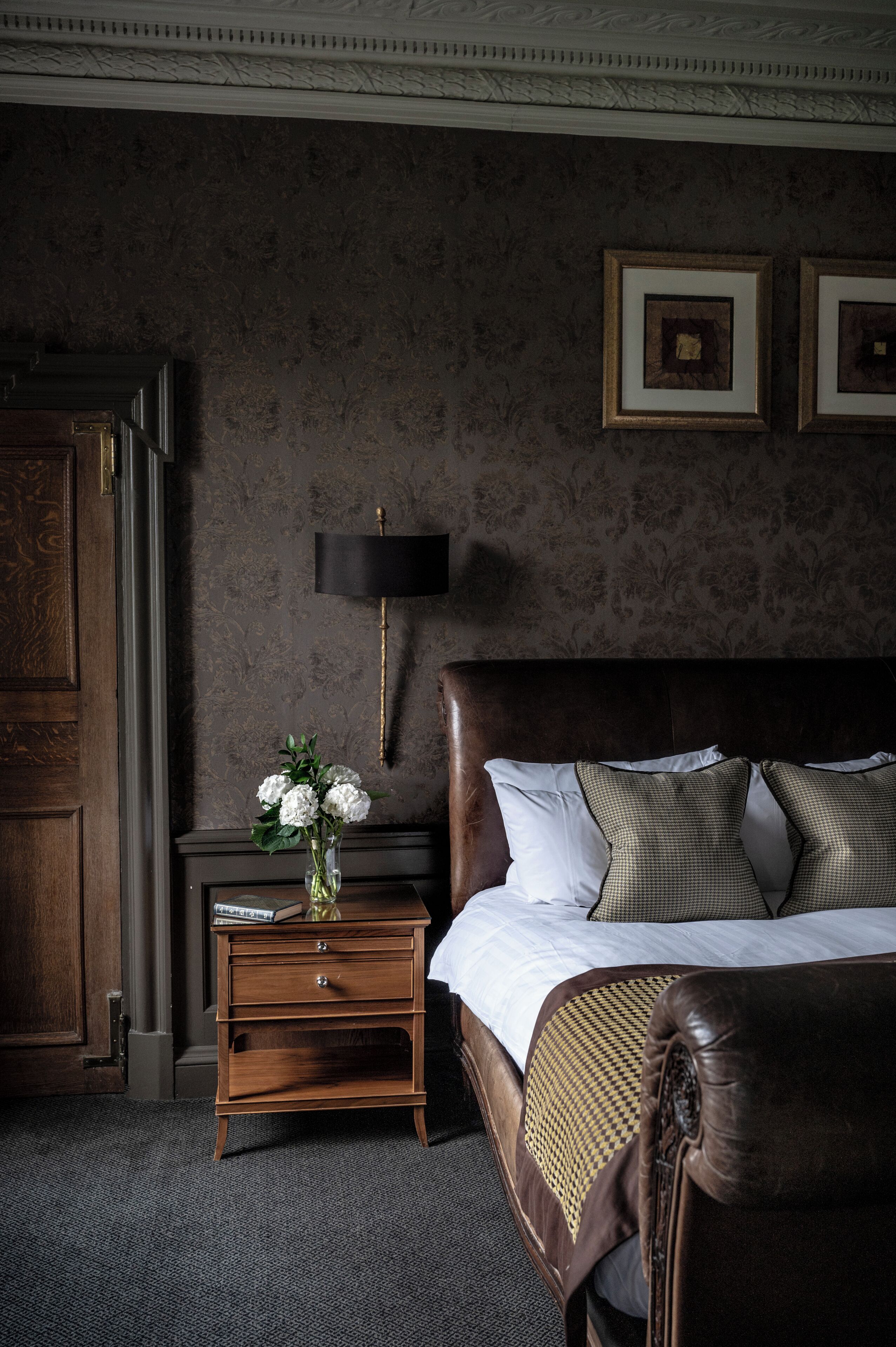 A bedroom with a large bed, a nightstand with a lamp, and a dresser.