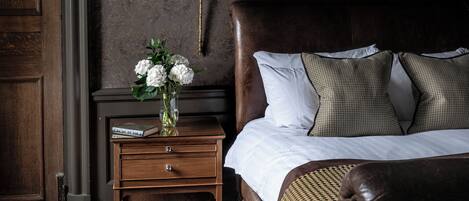 A bedroom with a large bed, a nightstand with a lamp, and a dresser.