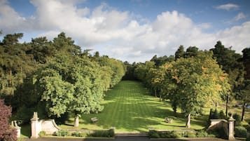 A formal garden with a central lawn, pathways, and benches.