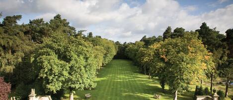 A formal garden with a central lawn, pathways, and benches.