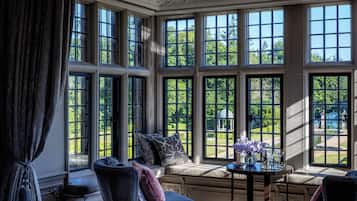 A room with large windows, a bench, and a small table with flowers.