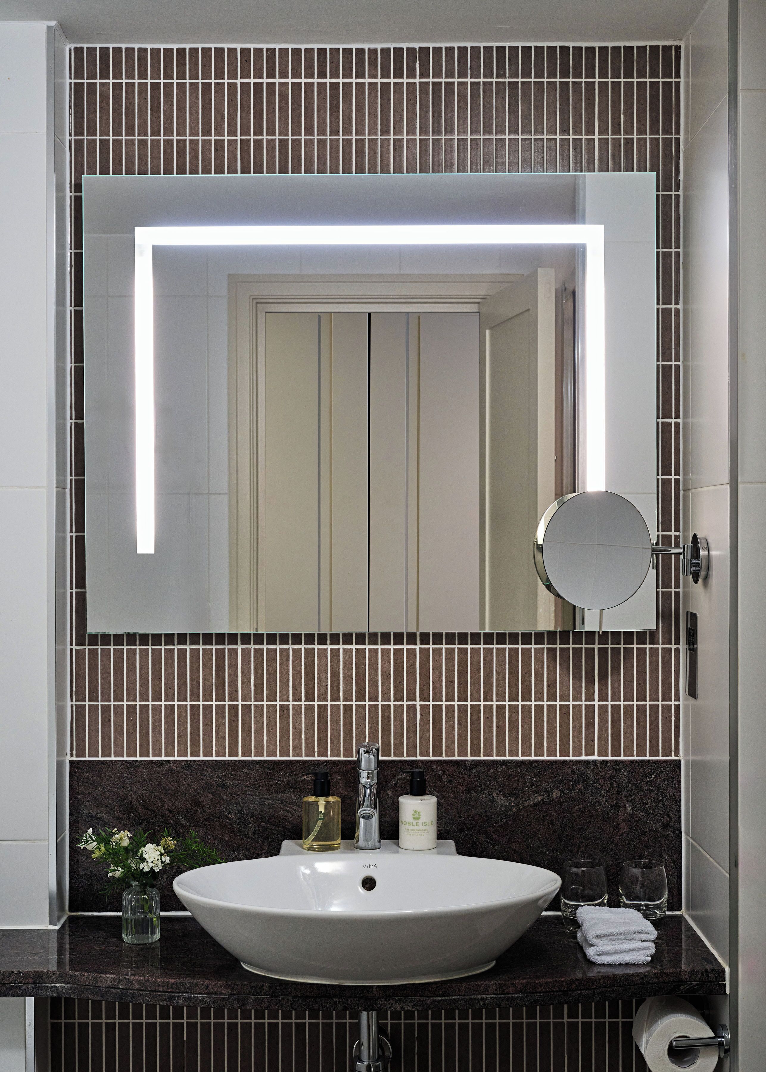 A bathroom with a white sink, a mirror, and a toilet paper holder.