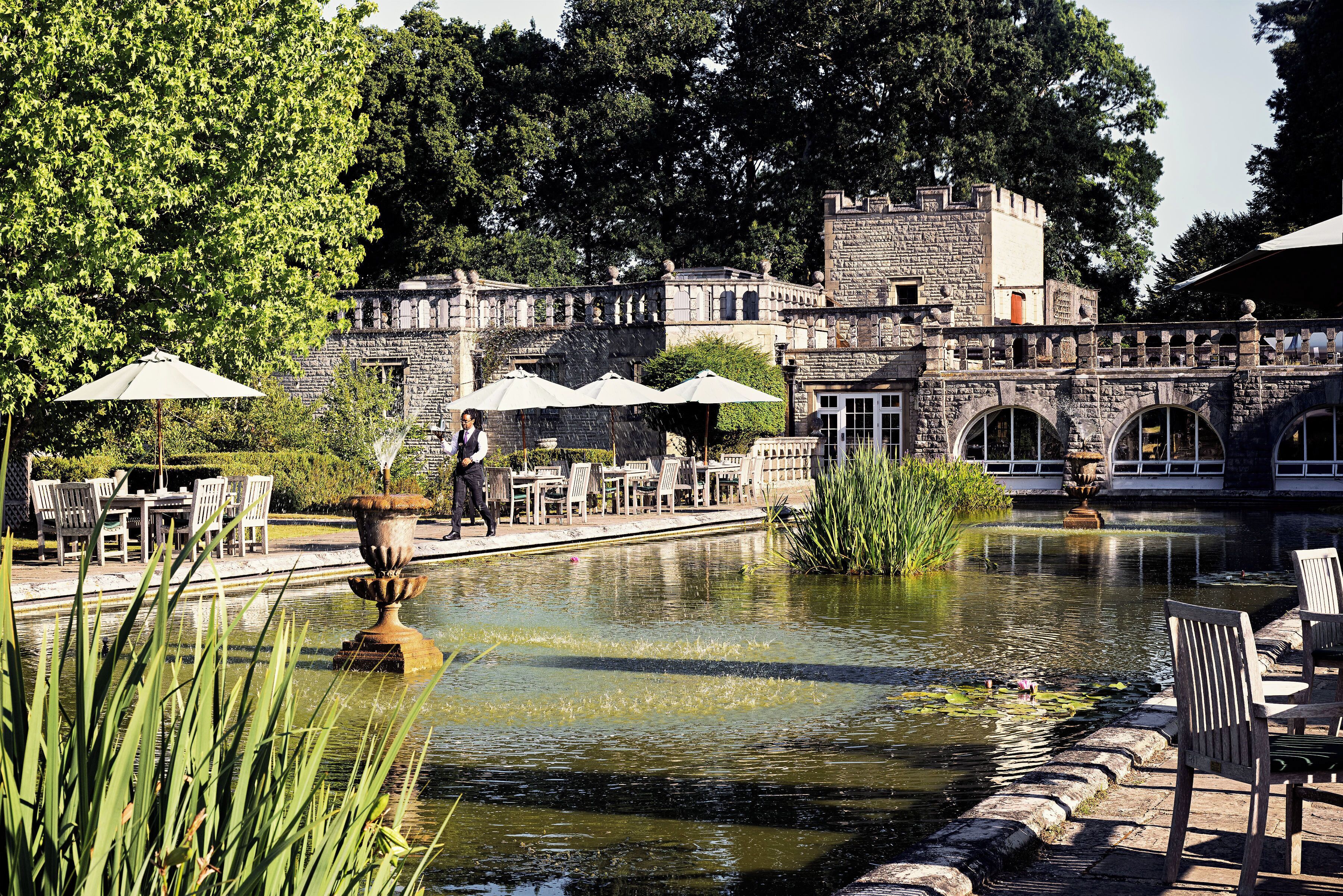 A courtyard with a pond, stone bridge, and outdoor seating area.