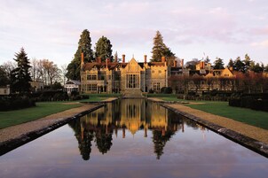 A large, historic building with a symmetrical facade, a central entrance, and a reflective water feature in front.