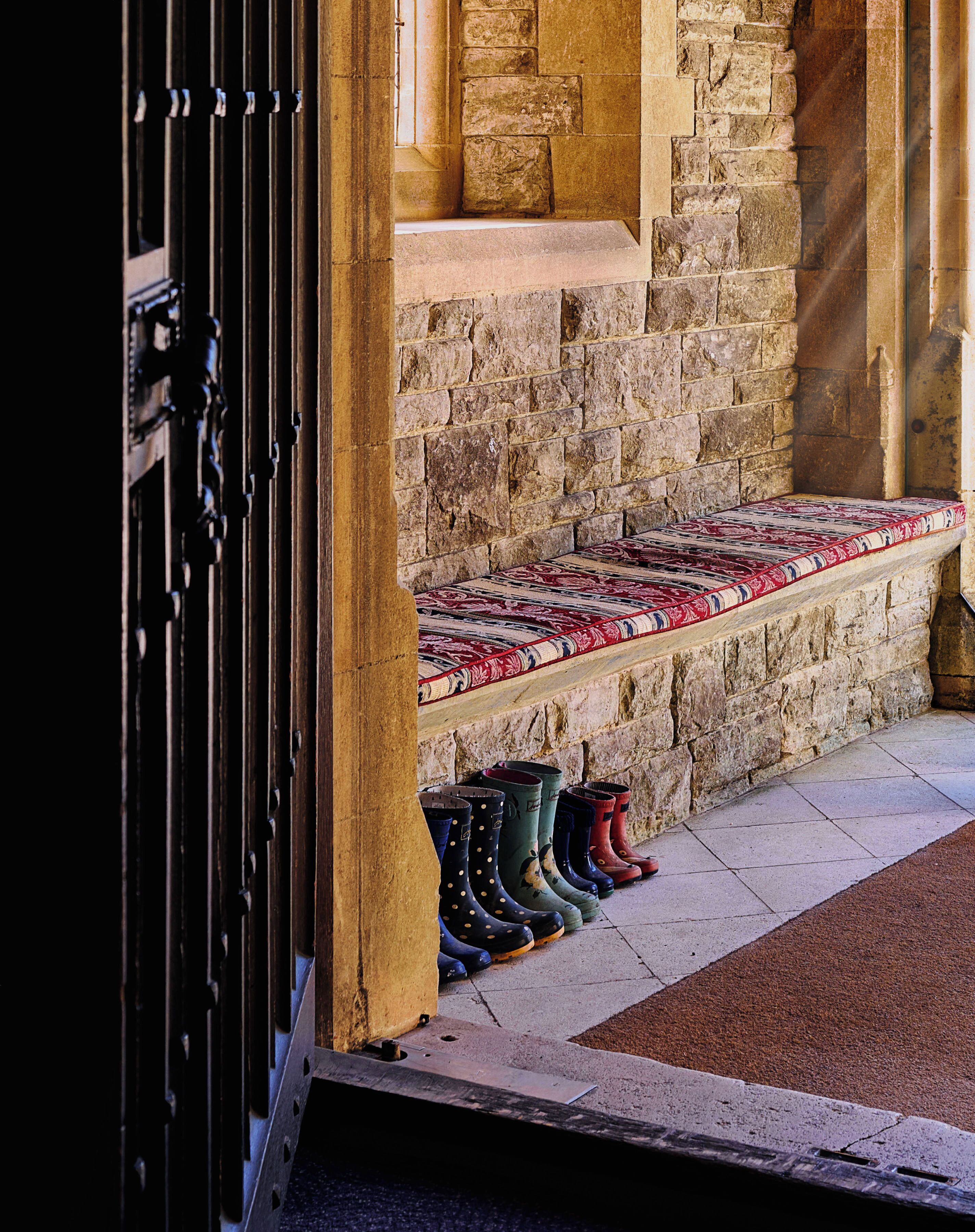 A stone wall with a bench and a row of boots.