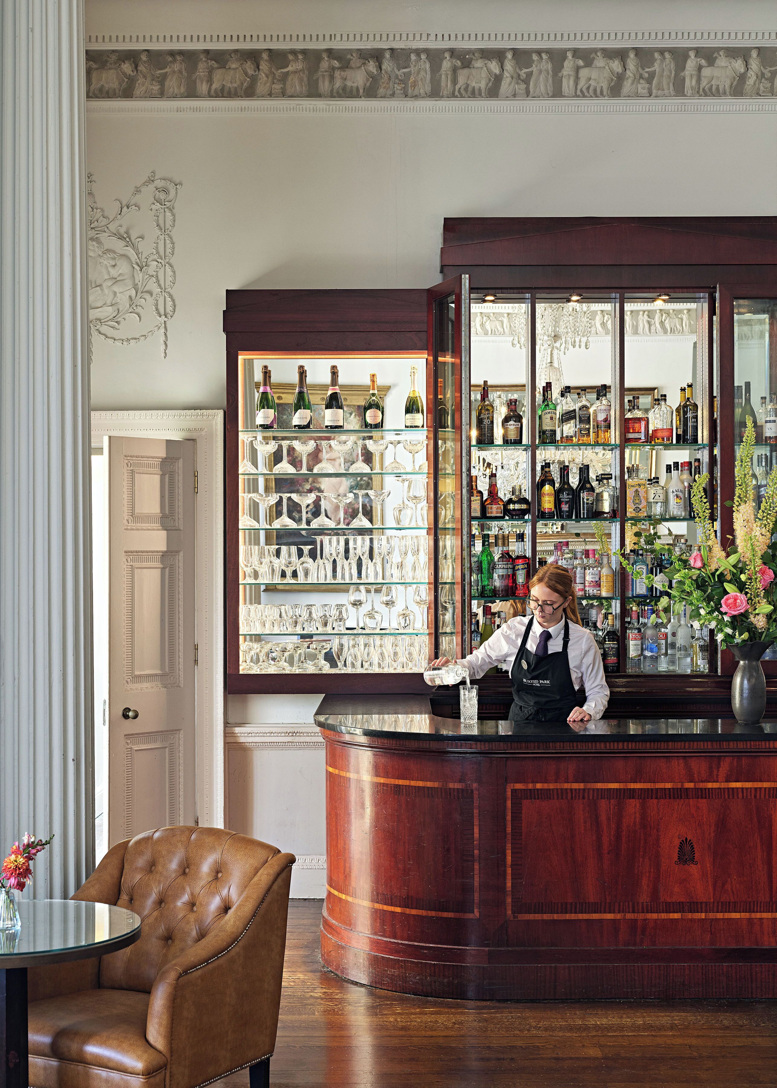 Eine Bar mit einem Barkeeper, Regalen voller Spirituosenflaschen und einer Dekoration an der Wand.