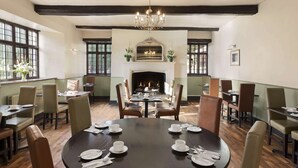 A dining room with a fireplace, wooden beams, and a chandelier. - Cwrt Bleddyn Hotel & Spa (Usk)