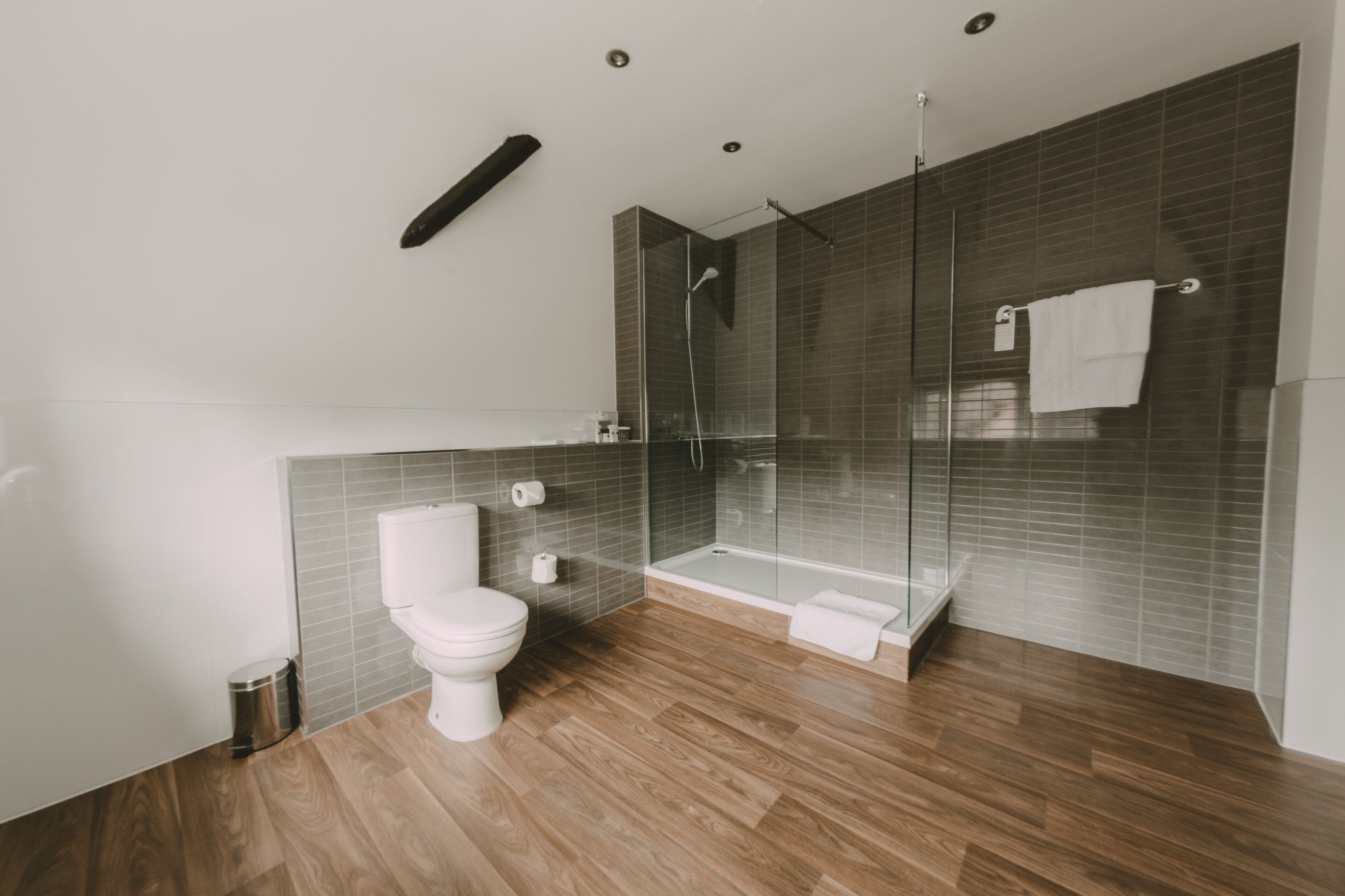 Un baño moderno con inodoro, ducha y zona de ducha con mampara de vidrio.
