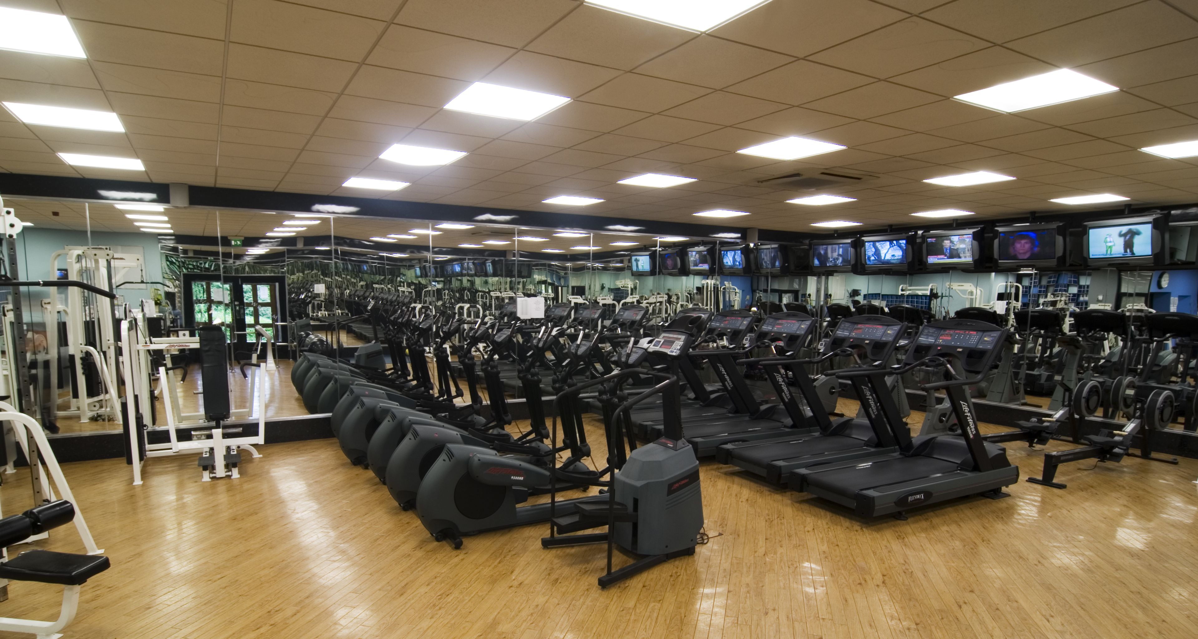 A gym with multiple treadmills, exercise bikes, and weight machines.