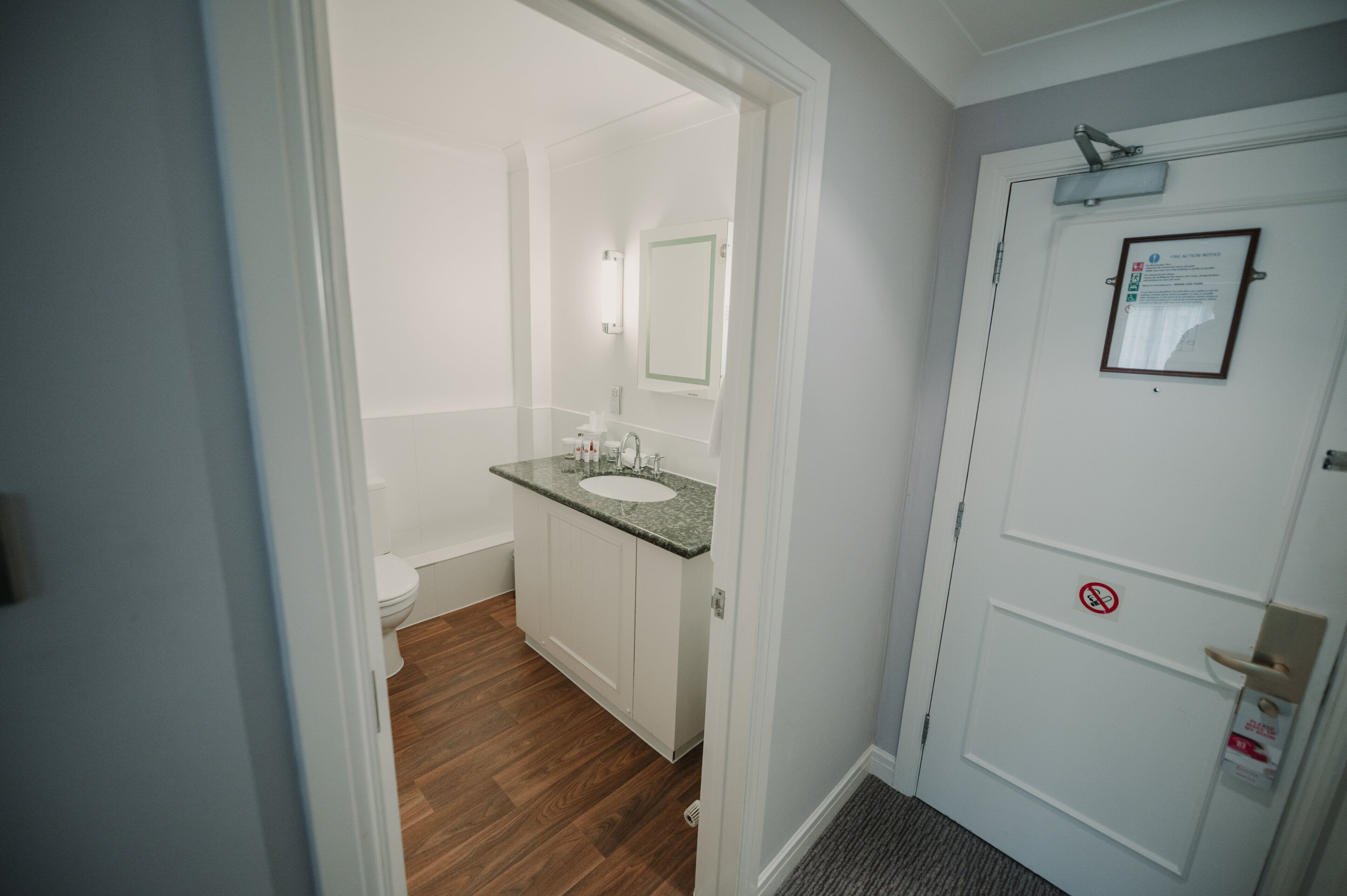 A bathroom with a white sink, mirror, and toilet.