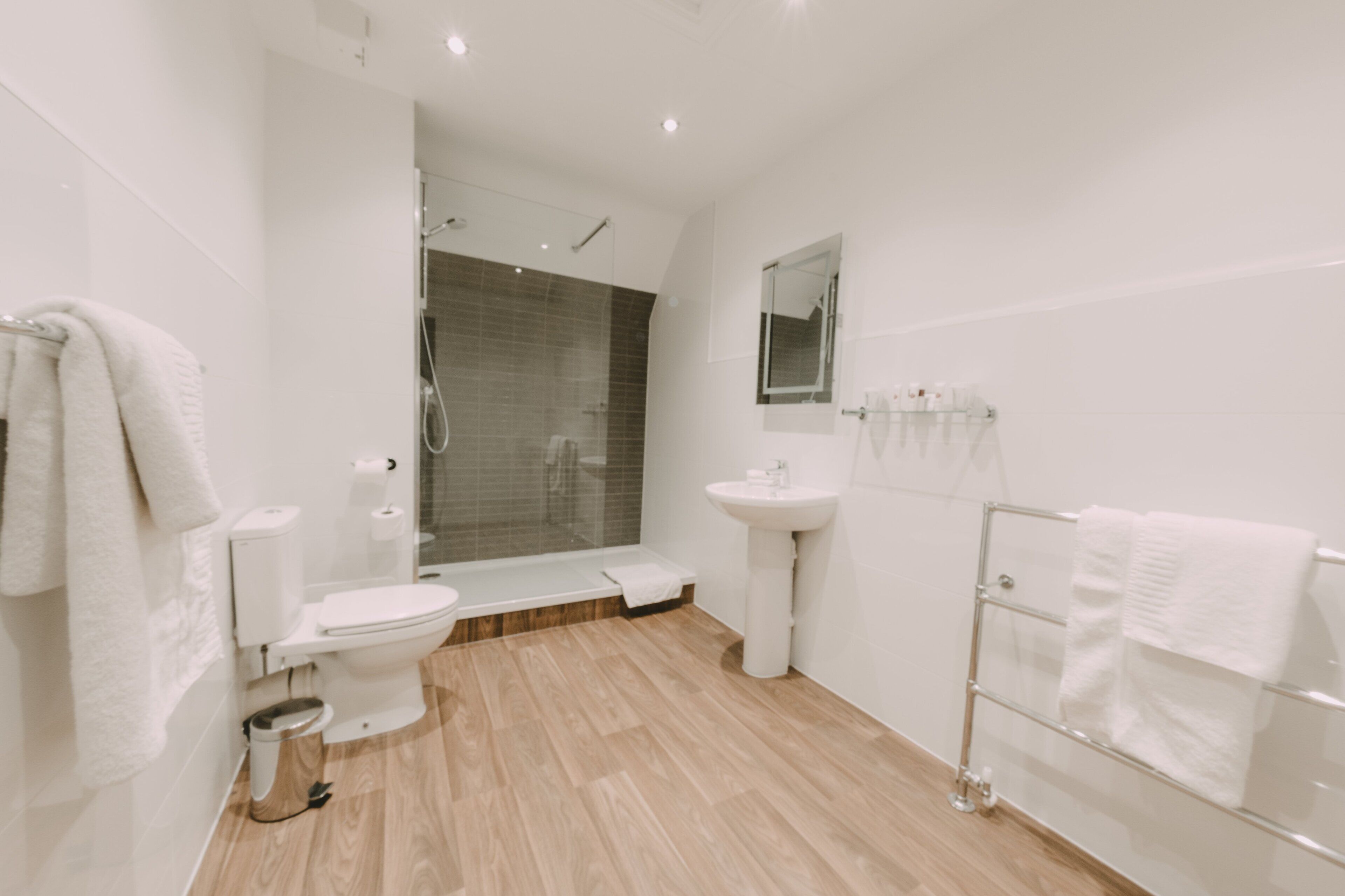 A modern bathroom with a toilet, sink, shower, and a glass-enclosed shower area.