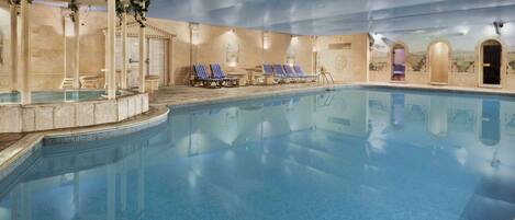 Una gran piscina interior amb gandules i una zona de banyera d'hidromassatge.