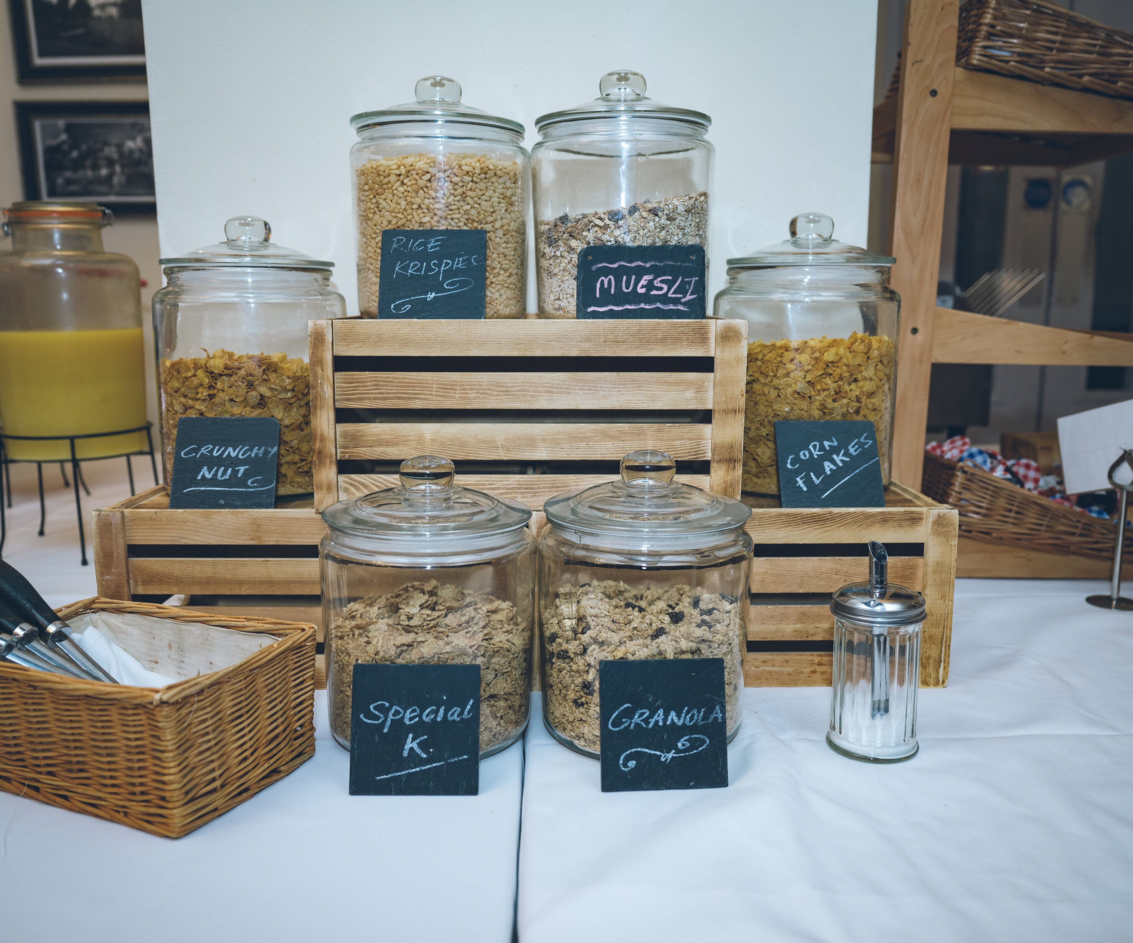 A display of food items in glass jars with labels, arranged on a table.