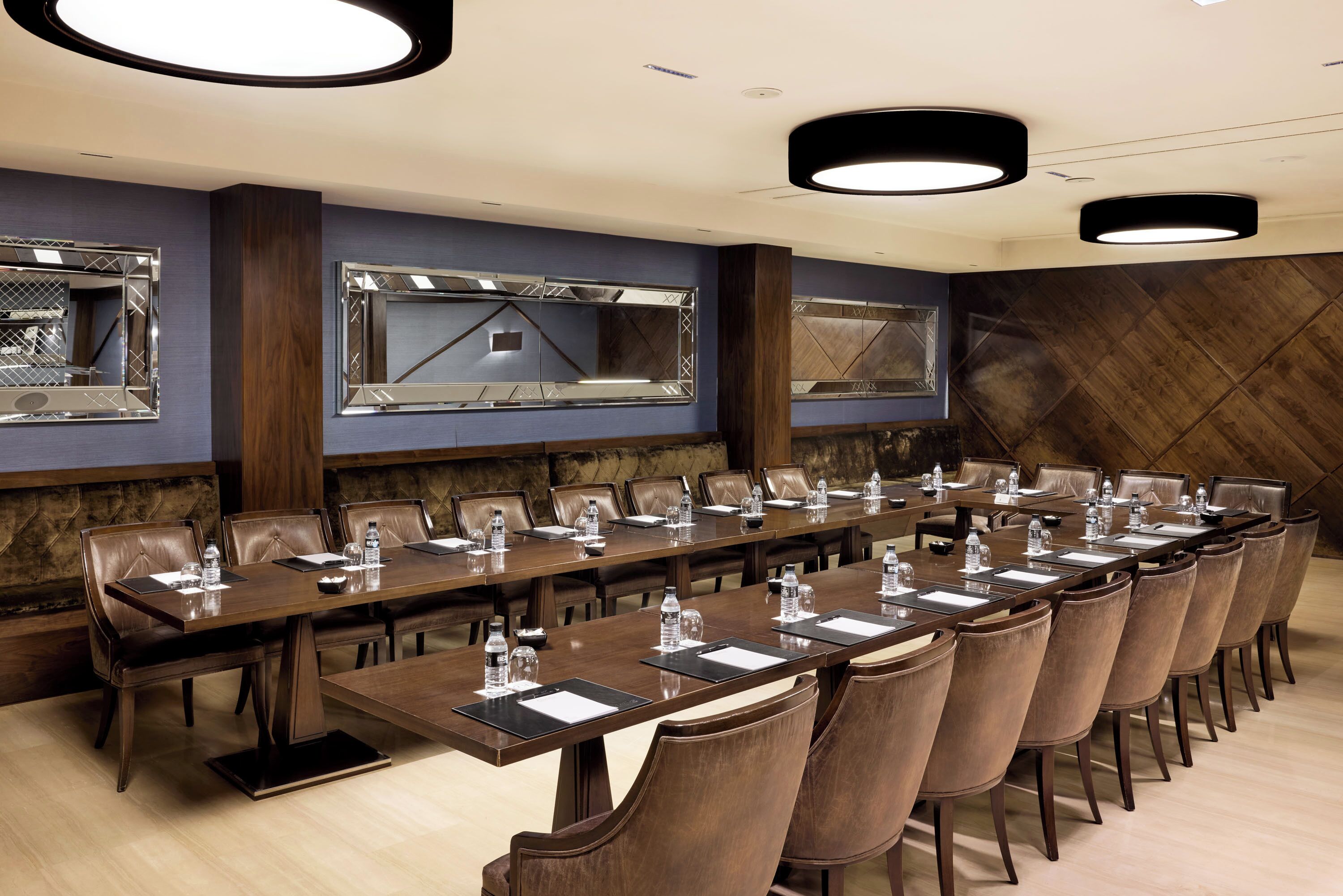 A conference room with a long table, leather chairs, and a large mirror.