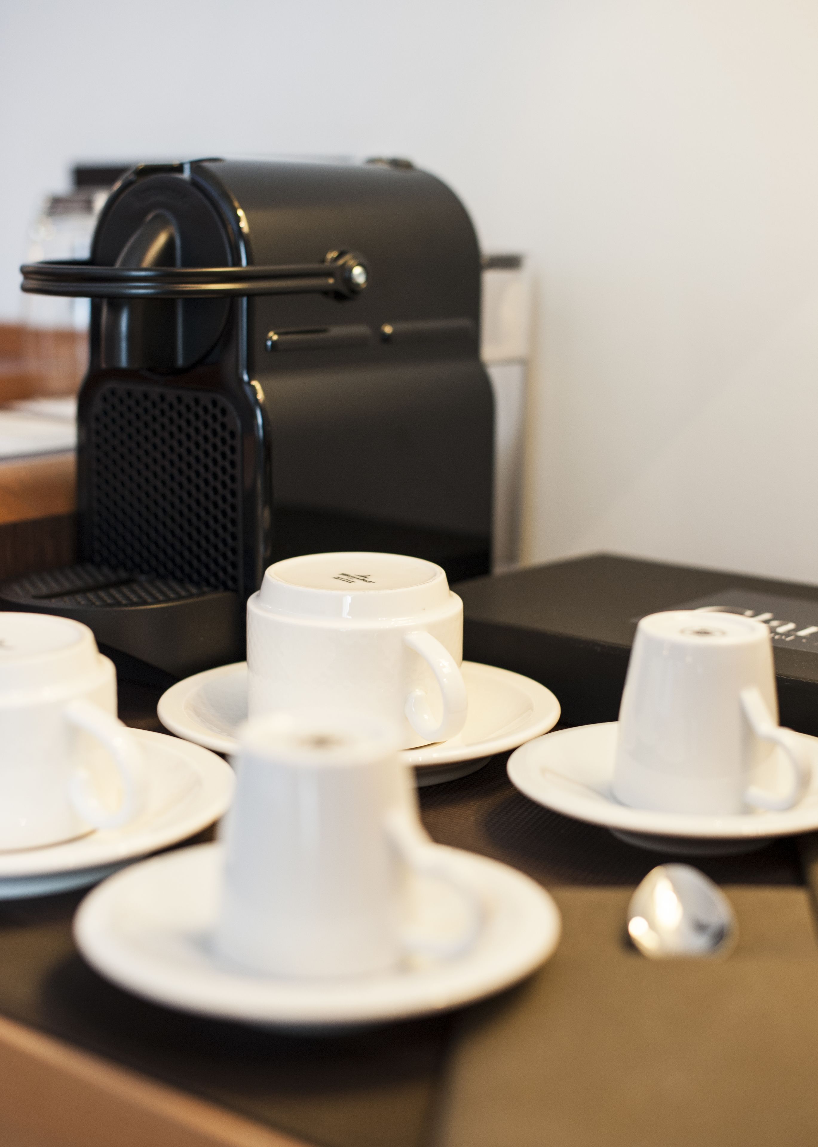 A coffee machine and several white cups on a table.