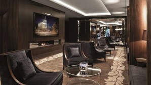 Un vestíbulo moderno con paneles de madera oscura, asientos cómodos, un televisor de pantalla plana grande y una alfombra estampada.