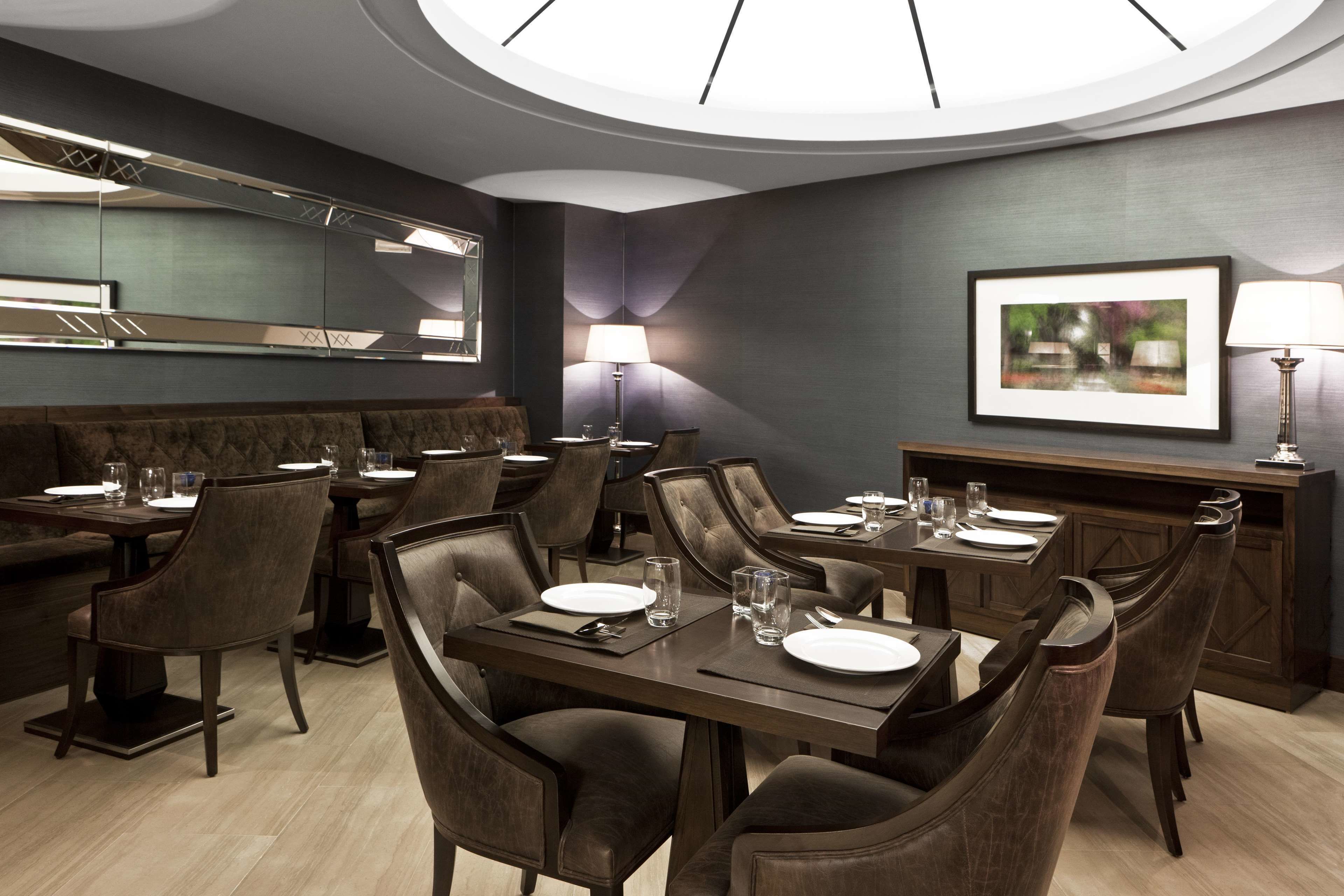 A modern dining area with a high ceiling, dark walls, and a central table with chairs.