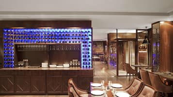 Un restaurante con una pared de vinos, muebles de madera y una zona de bar.