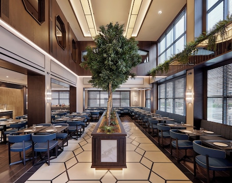 Un restaurant spacieux doté d’un grand jardinier central, de plusieurs espaces de détente et de grandes fenêtres laissant entrer la lumière naturelle.. Hotel Claridge Madrid