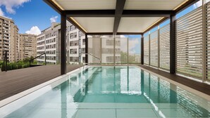 Una piscina interior moderna con agua cristalina, rodeada de balcones y grandes ventanales.