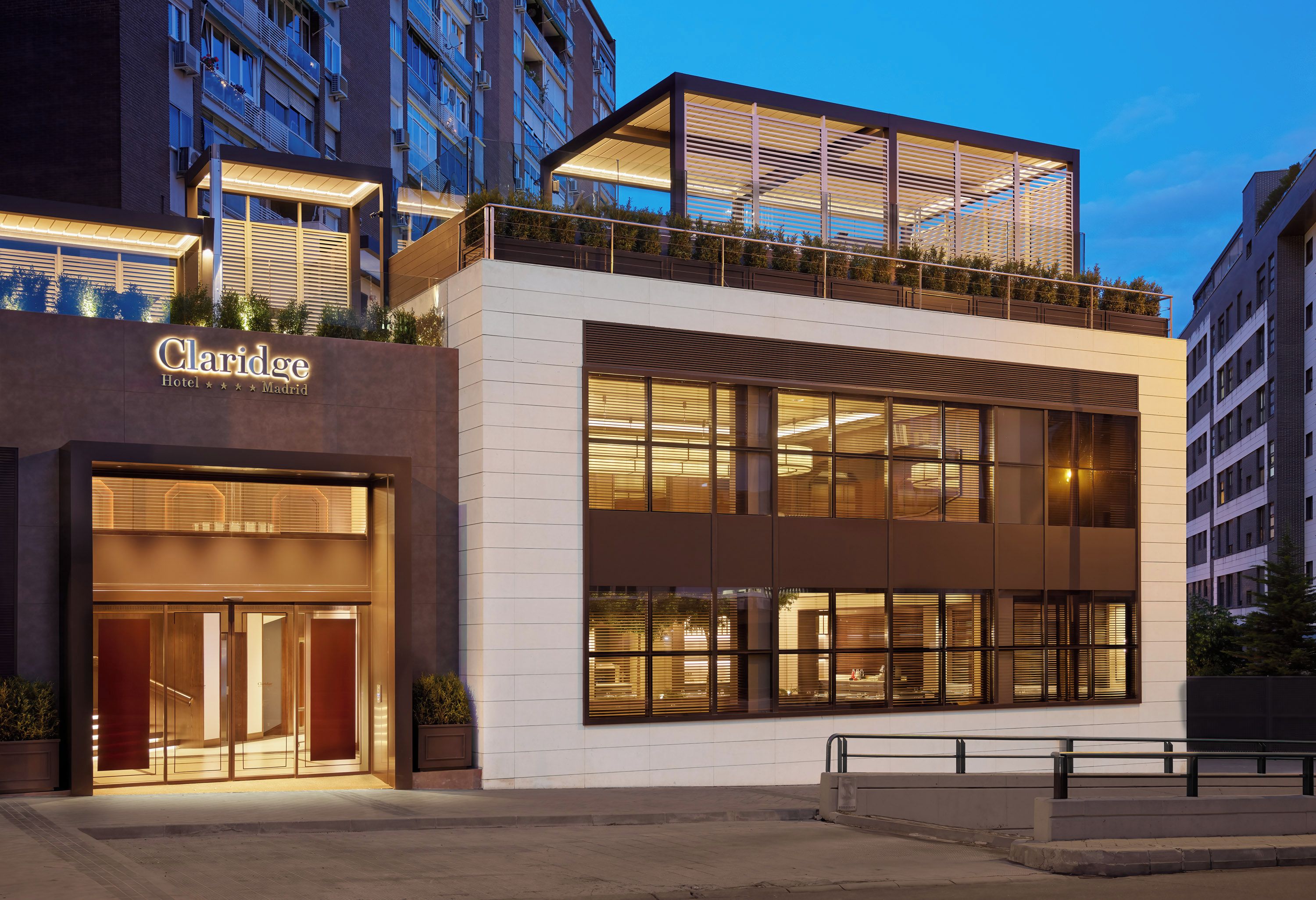A hotel with a modern facade, large windows, and a sign indicating it is located in Madrid.