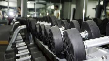 A row of black dumbbells on a rack in a gym.