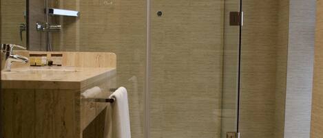 A modern bathroom with a glass-enclosed shower, a marble sink, and a toilet.