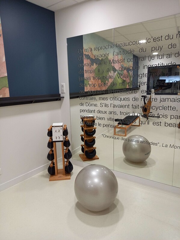 A room with a large mirror reflecting a wall with text and a sculpture. There is a rack with black bags and a large white sphere sculpture.