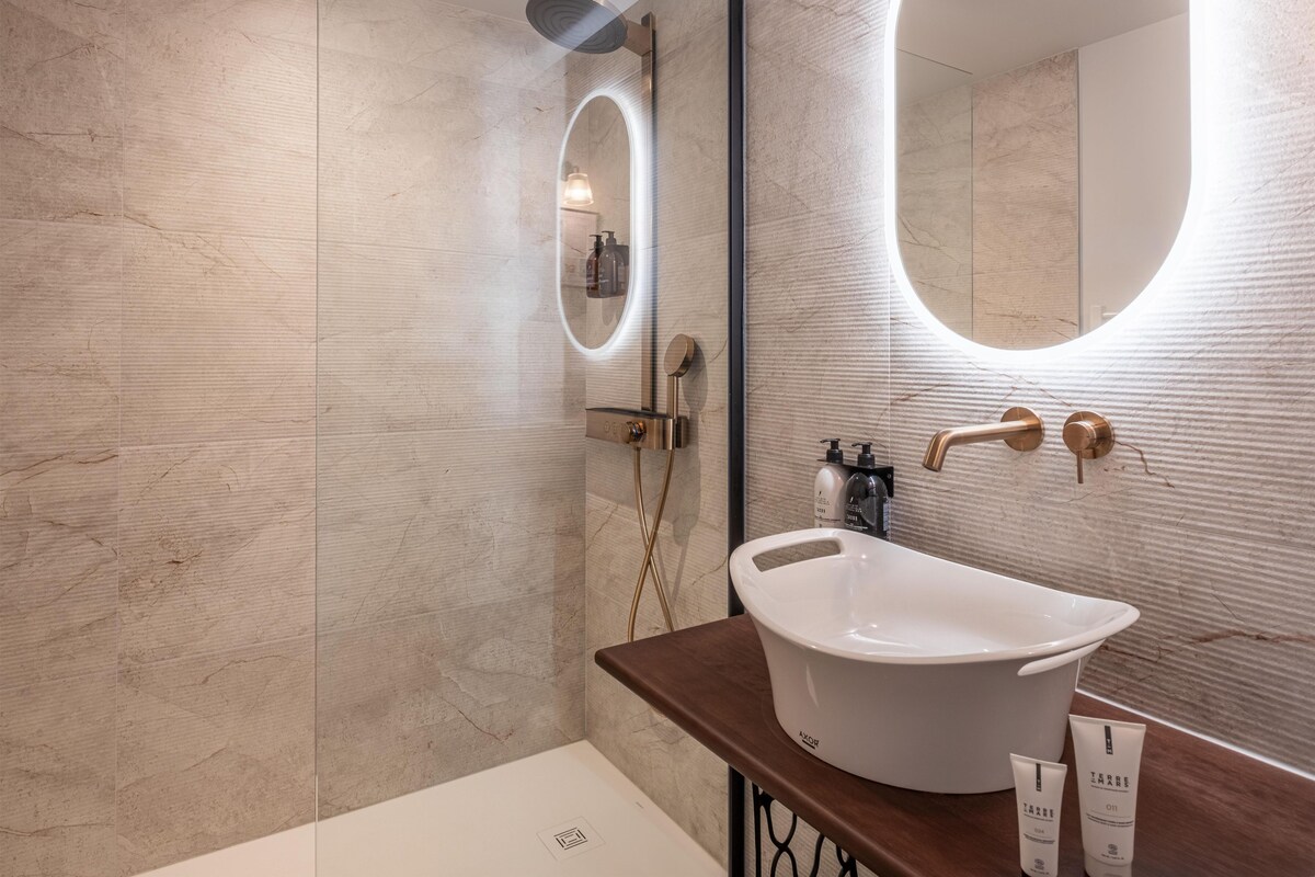A modern bathroom with a freestanding bathtub, a large mirror, and a wall-mounted sink.