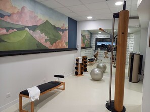 A room with a bench, exercise balls, and a wooden pole.