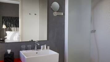 Ein modernes Badezimmer mit einem weißen Waschbecken, einem runden Spiegel und einer roten Kommode.