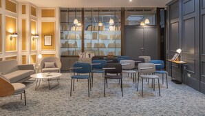 Un área de descanso moderna con sofá, sillas, una mesa de centro y una estantería llena de libros.