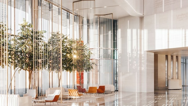 Un hall d’entrée spacieux, agrémenté d’un grand arbre, de sièges modernes et d’un sol réfléchissant.