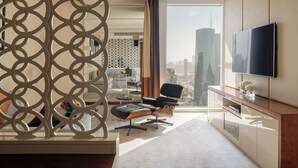 Une chambre d’hôtel moderne dotée d’une grande fenêtre, d’un téléviseur à écran plat, d’un canapé en cuir et d’une console en bois.