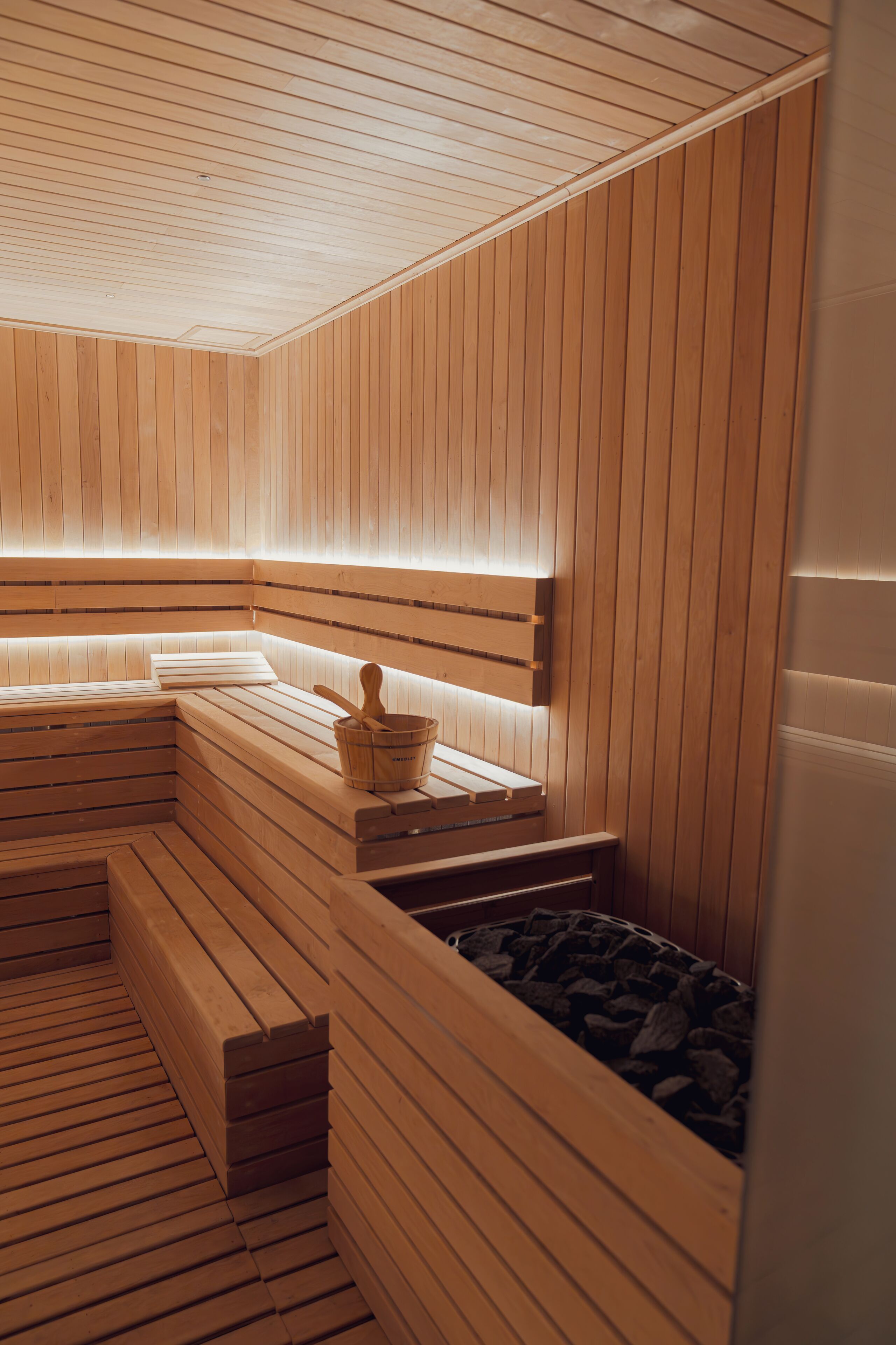 En sauna med træbænke og en stenbasseng.