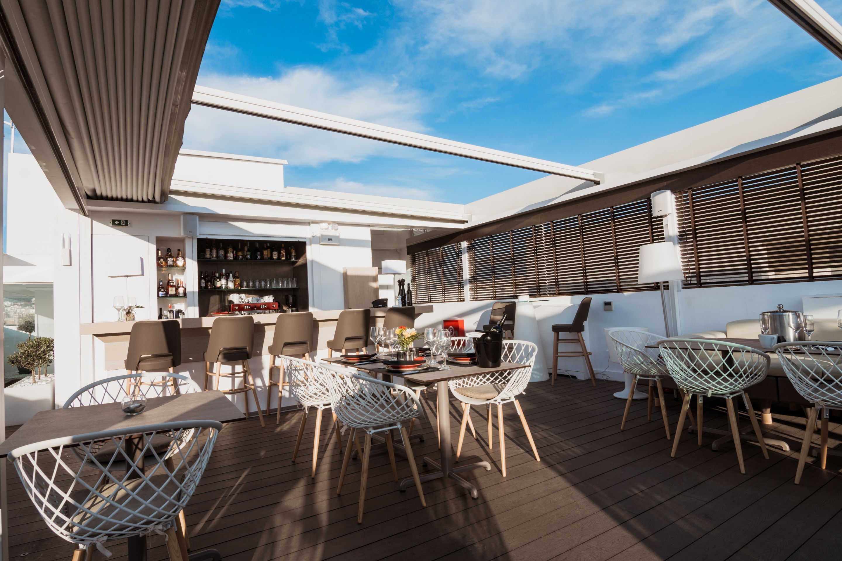 An outdoor deck with a bar area, seating, and a view of the sky.