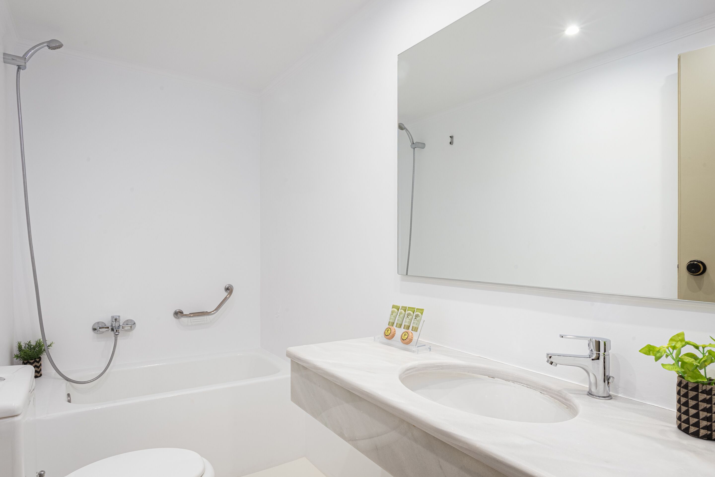 A modern bathroom with a bathtub, toilet, sink, and a large mirror.