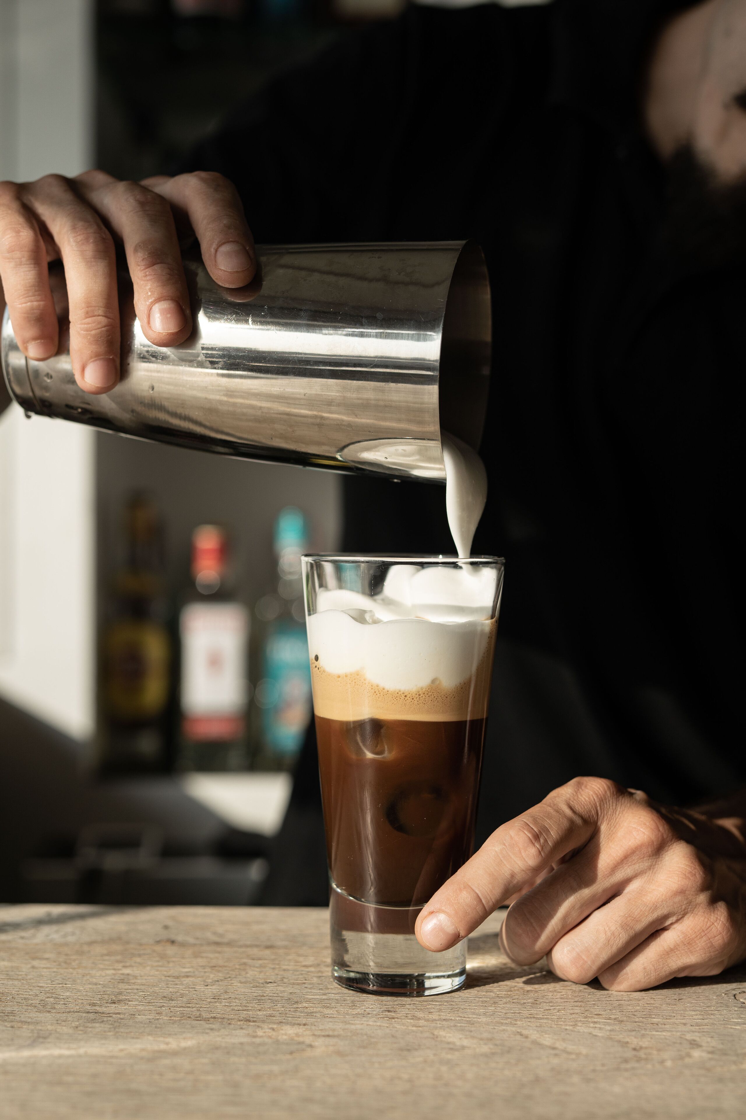 Una persona abocant llet en un got de cafè amb gel.