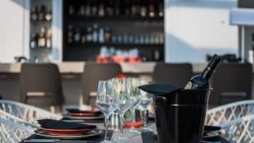 A table set with wine glasses, a black bottle in a holder, and red plates.