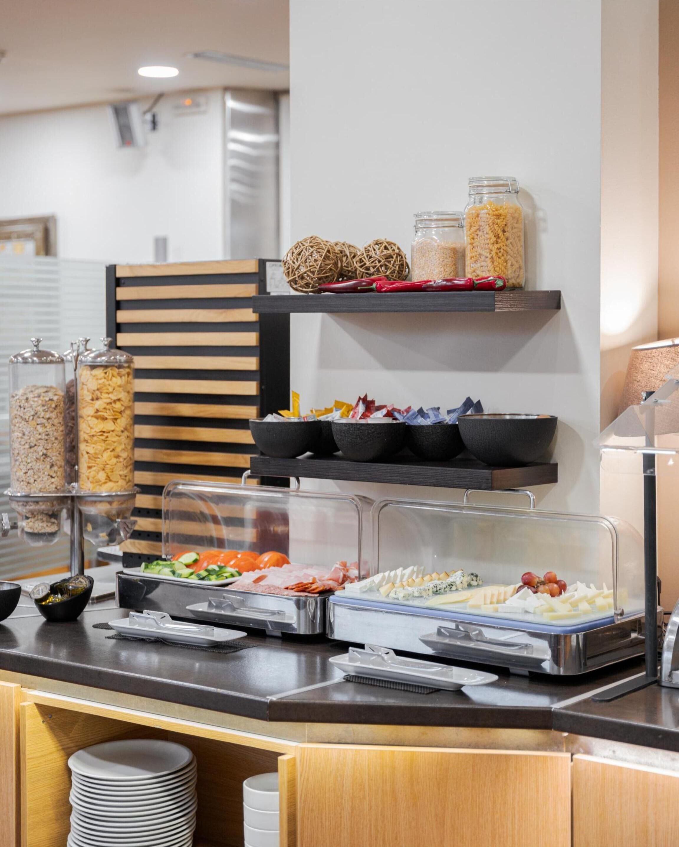 A buffet setup with various food items, including cereals, fruits, and cheeses, displayed on shelves and in containers.