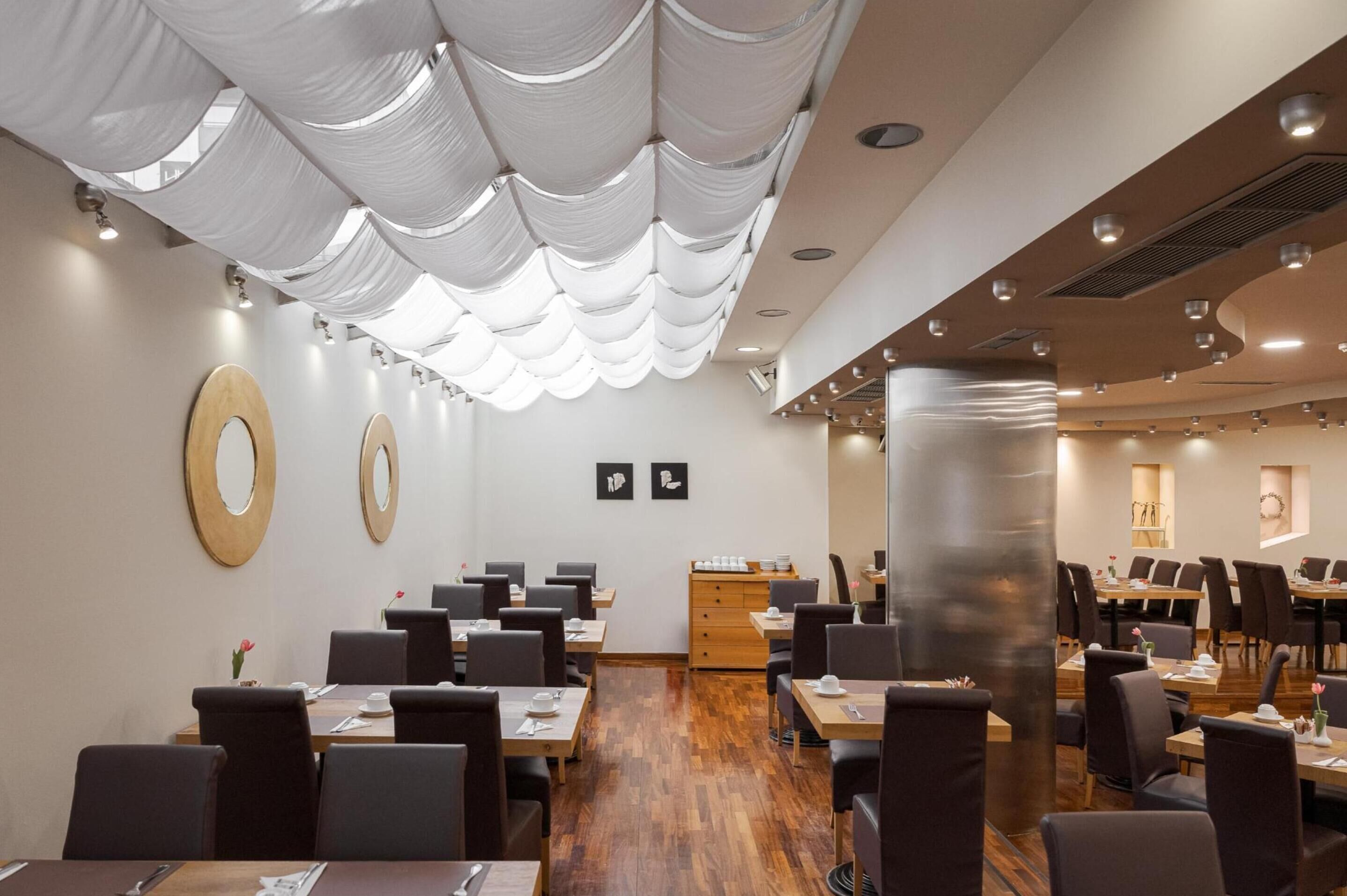 Un salón de conferencias con mesas redondas, sillas y un armario de madera.