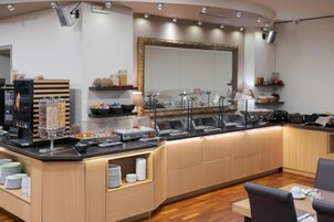 Un comptoir pour le petit-déjeuner équipé de plusieurs distributeurs de nourriture, d’une machine à café et d’un miroir placé au-dessus.